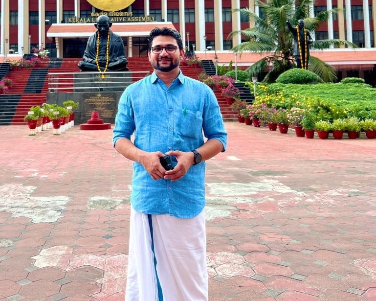 Portrait Of Smiling Male College Student In Busy Communal Campus Building